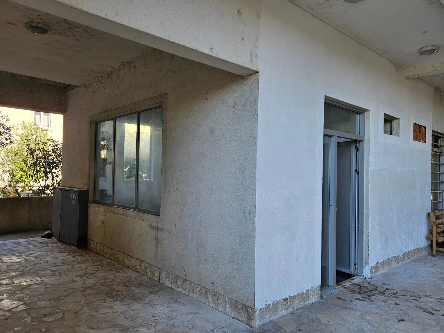 Exterior view of the building with a porch and stone paving.