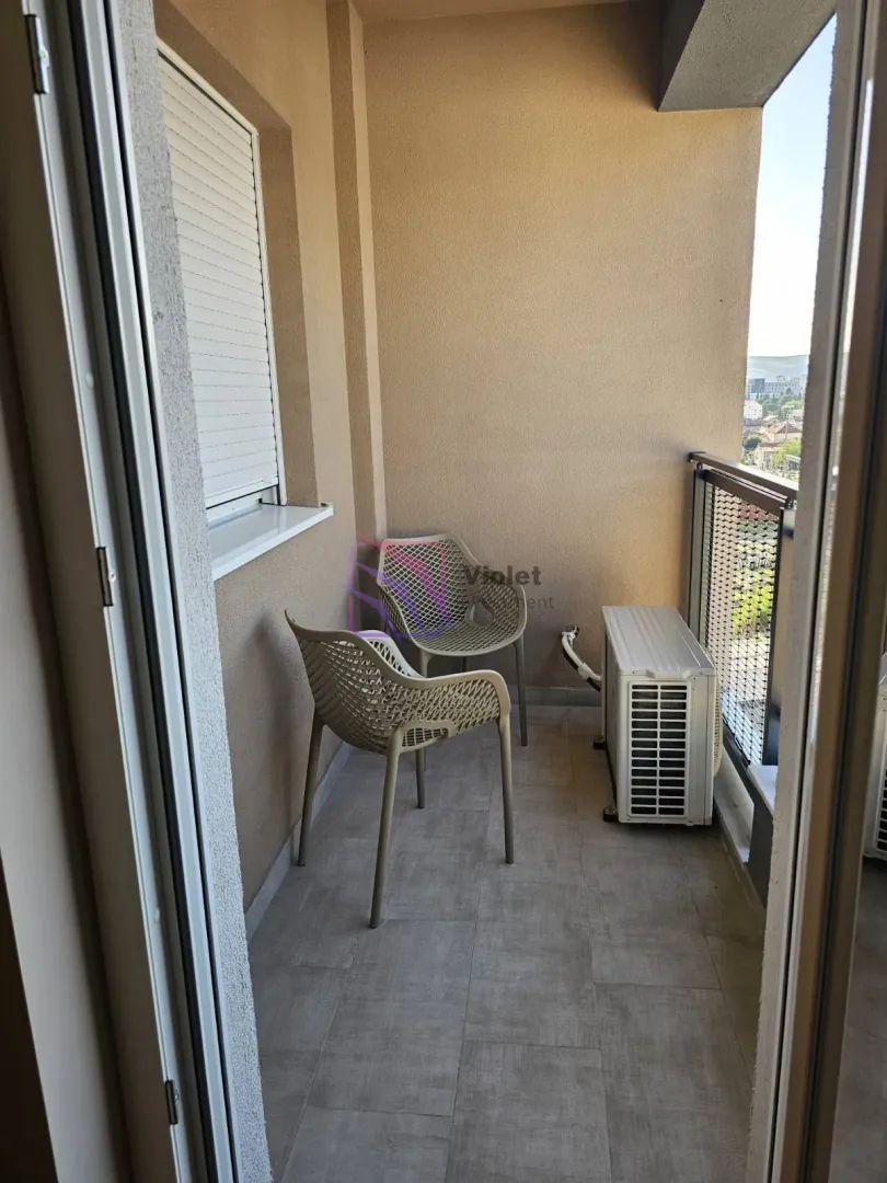 Smaller balcony with two chairs and an air conditioning outdoor unit.