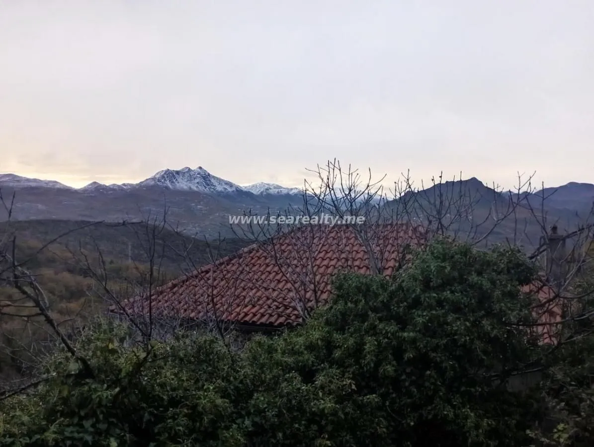 Pogled na planinske vrhove sa dijelom krova i prirode u prvom planu.