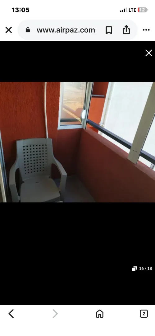 Manji balkon sa plastičnom stolicom i crvenom fasadom.