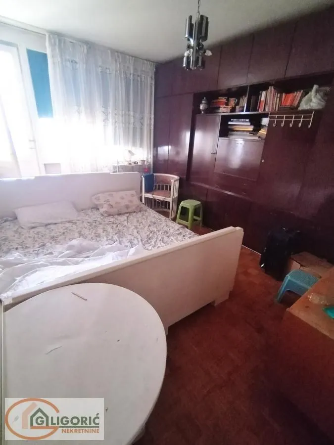 Nameštena spavaća soba sa bračnim krevetom i ugradnim ormarom.