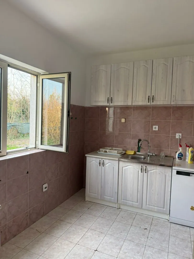 A simple kitchen with light-colored cabinets and an open window.
