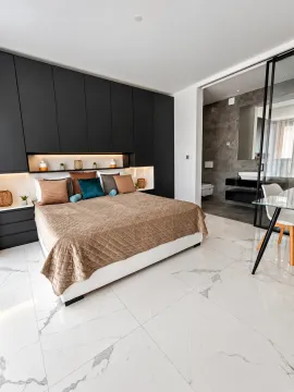 Modern bedroom with a double bed, built-in wardrobes, and a view into the bathroom. - image 15