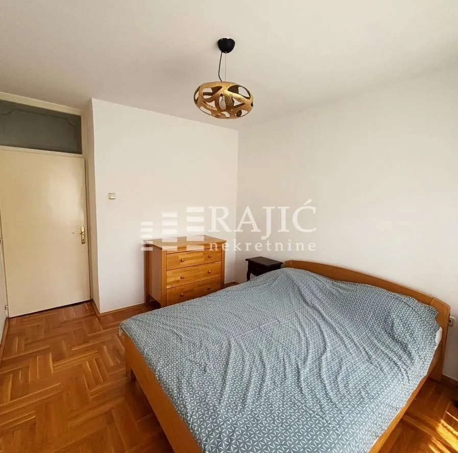Furnished bedroom with a double bed and wooden flooring.