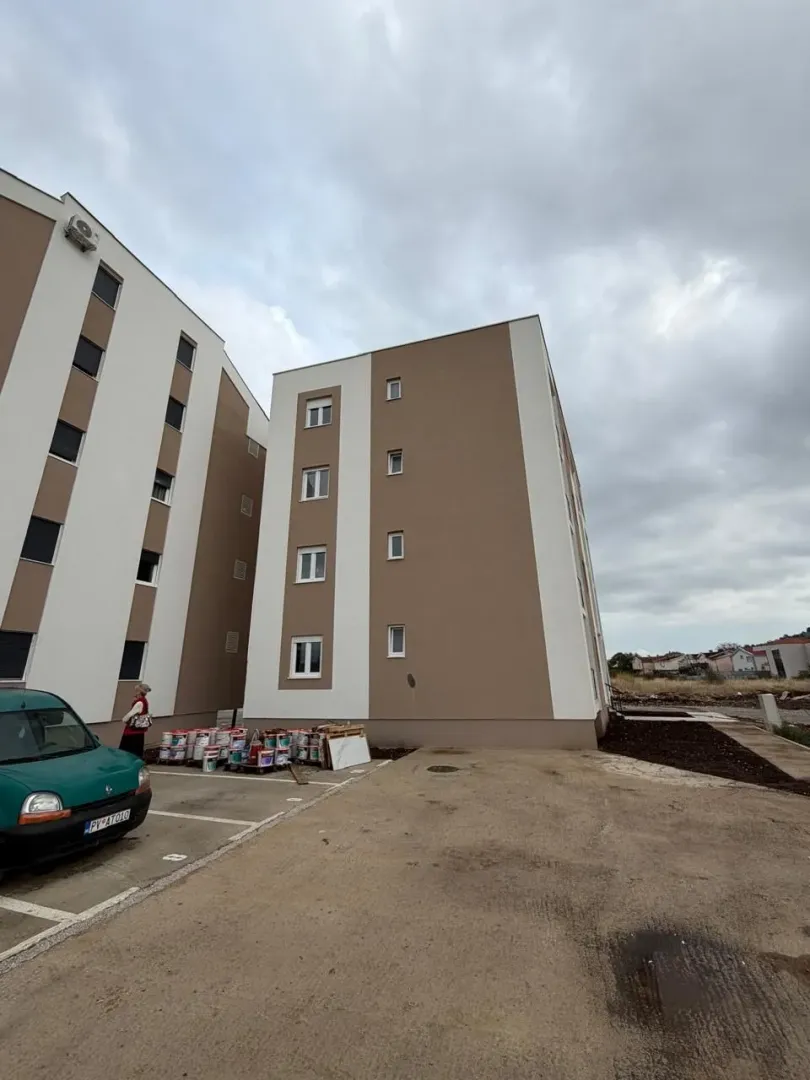 Exterior view of a residential building with parking and yard.
