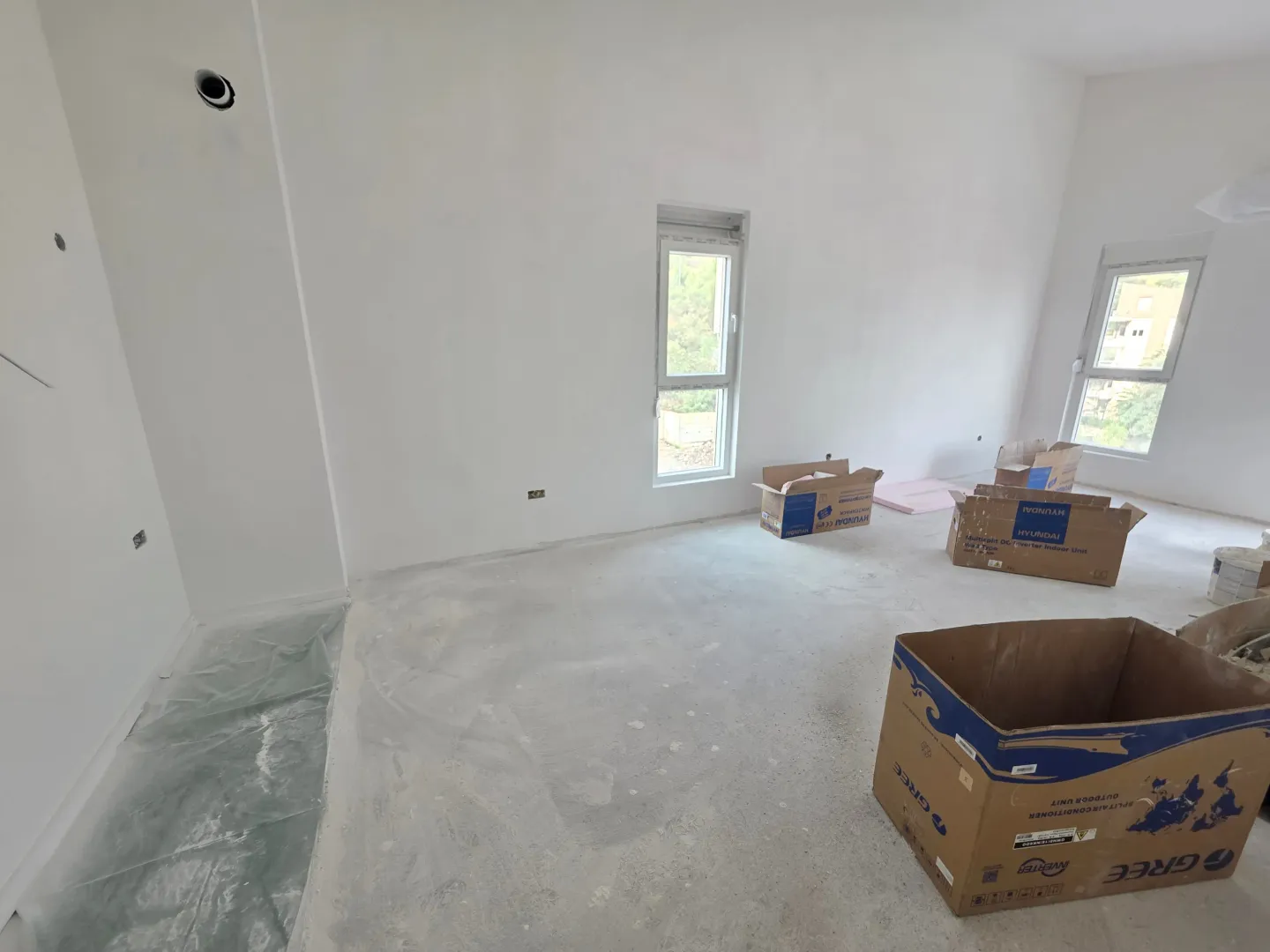 Empty room under construction with white walls and cardboard boxes on the floor.
