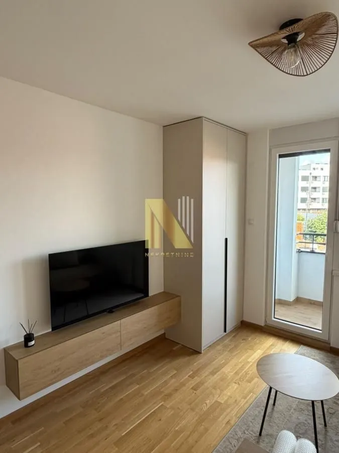 Living room with a TV, wardrobe and access to the terrace.