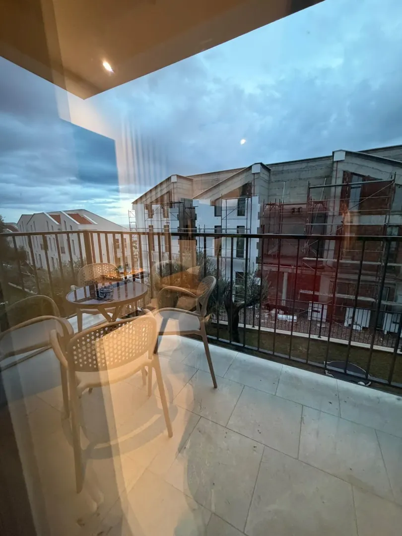 Furnished balcony with seating set and view of surrounding buildings.