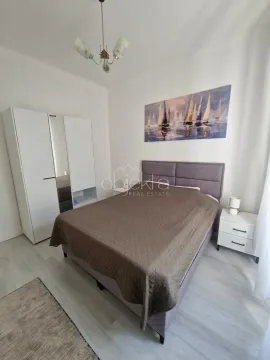 Namještena spavaća soba sa bračnim krevetom, ormarom i bijelim noćnim stočićima. - image 9
