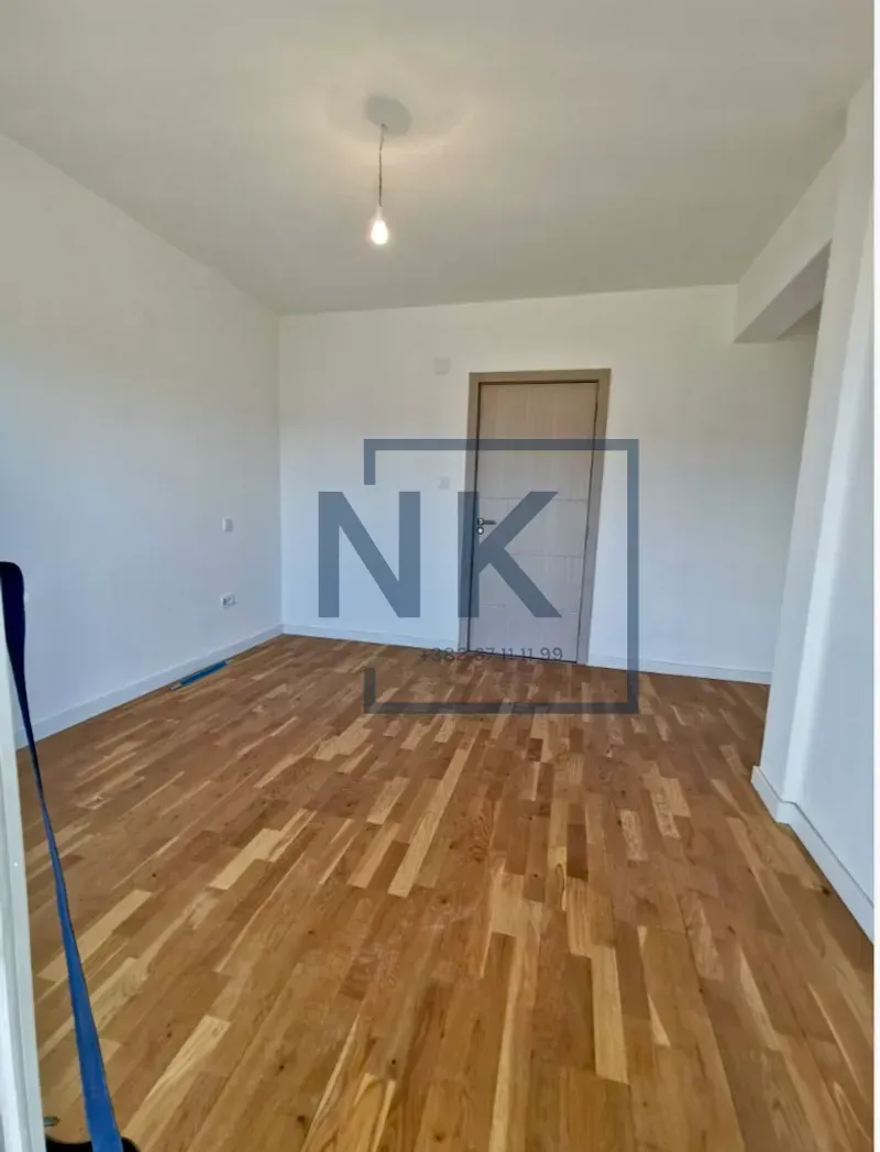 An empty room with wooden flooring and white walls.