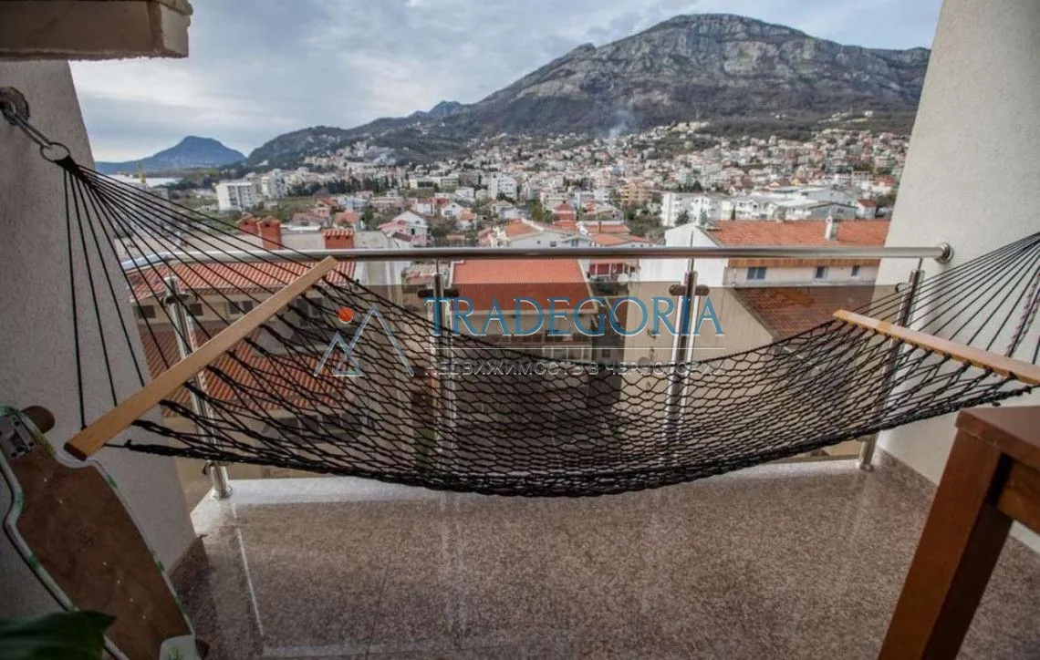 Terasa sa ležaljkom i pogledom na grad i planine.