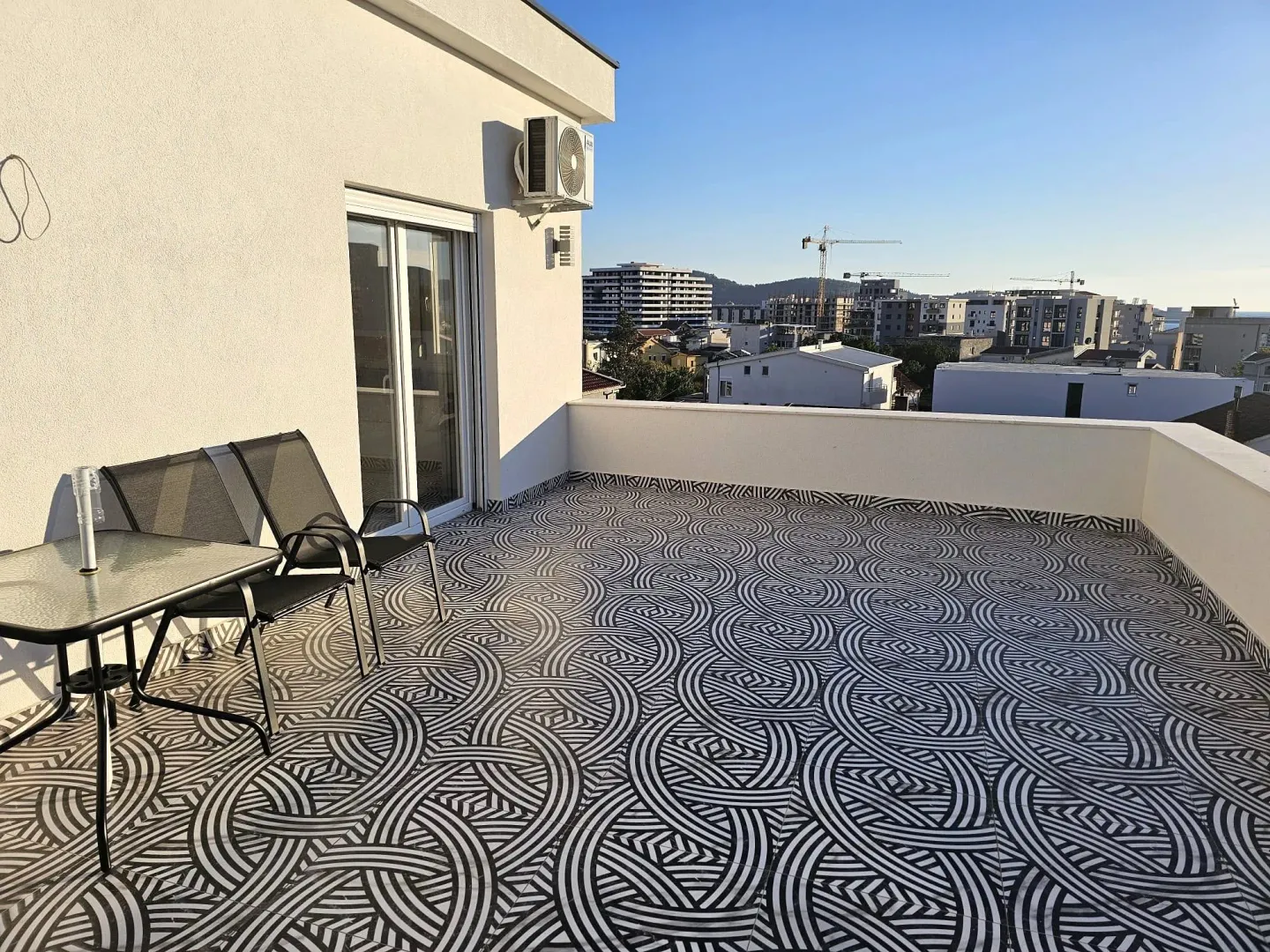 Spacious terrace with black and white tiles and patio furniture.
