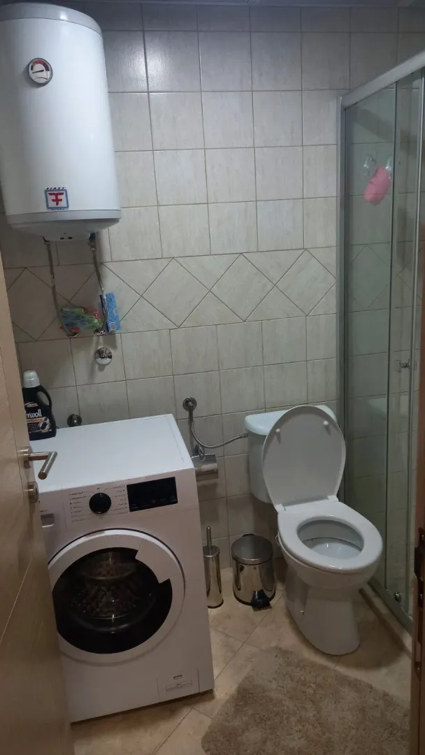 Jednostavno kupatilo sa veš mašinom, bojlerom i tuš kabinom.