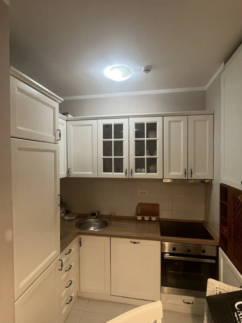 Bright kitchen with white cabinets, built-in oven, and a sink.