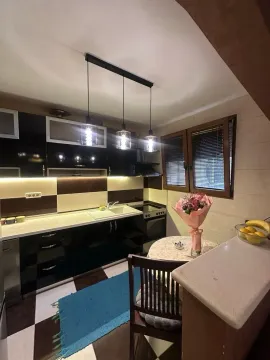 Moderna kuhinja sa crnim elementima, trpezarijskim stolom i visećom rasvjetom. - image 4