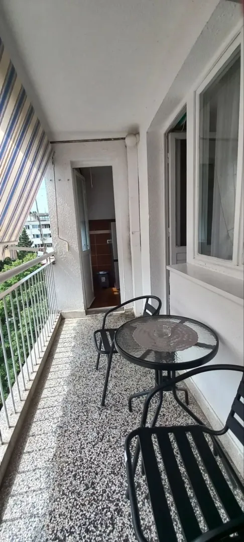 A balcony with a round table and two chairs.