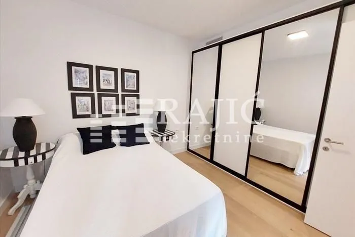 Furnished bedroom with a double bed and a large built-in wardrobe with a mirror.