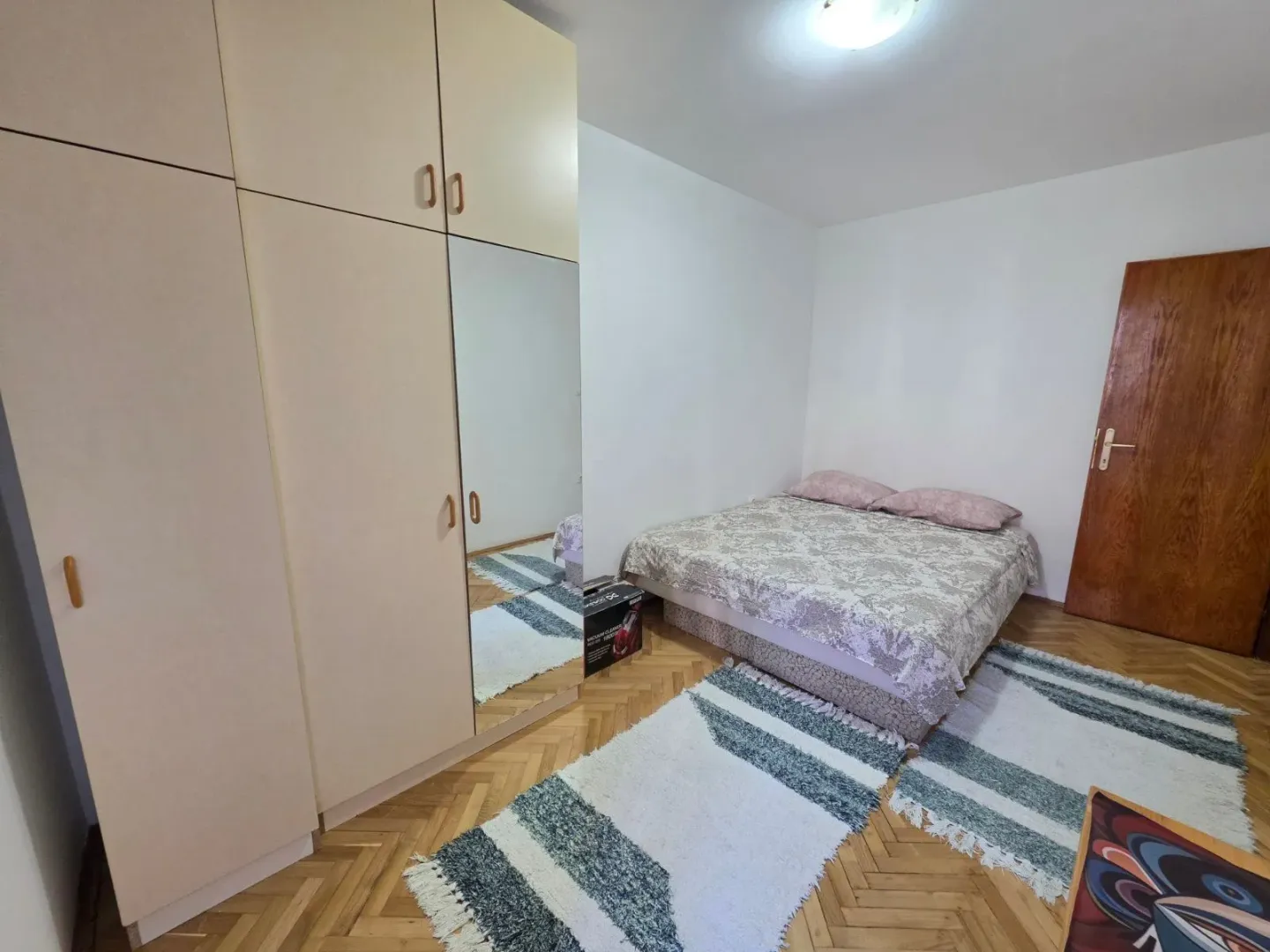 Bedroom with a double bed, large wardrobe, and wooden flooring.