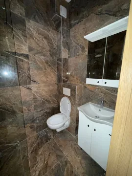 Manje kupatilo obloženo tamnim keramičkim pločicama sa sanitarijama i ogledalom. - image 6