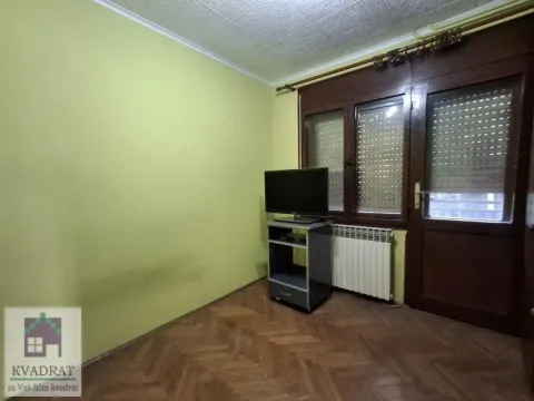 Dnevna soba sa drvenim parketom, televizorom i vratima koja vode na terasu. - image 17
