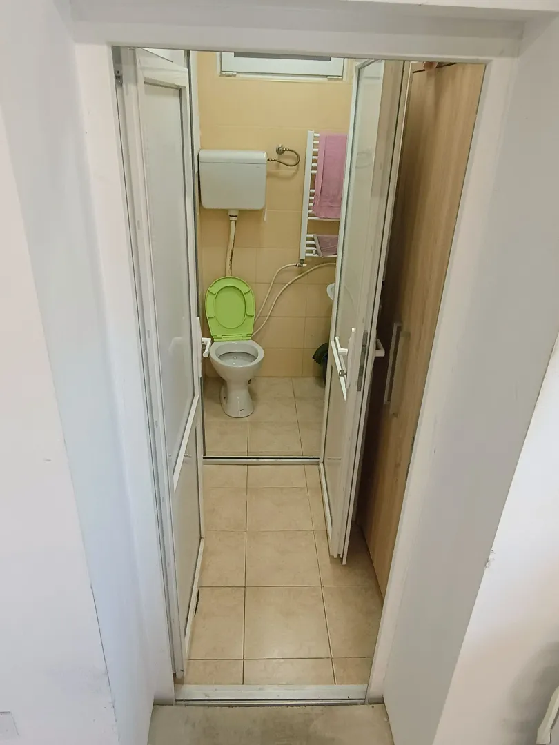 Smaller bathroom with toilet and beige tiles.