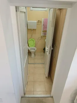 Smaller bathroom with toilet and beige tiles. - image 15