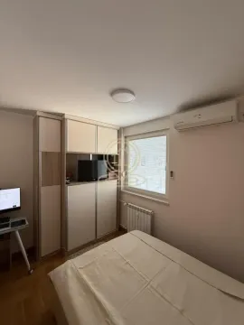 Furnished bedroom with a bed, wardrobe, desk, and air conditioning unit. - image 6