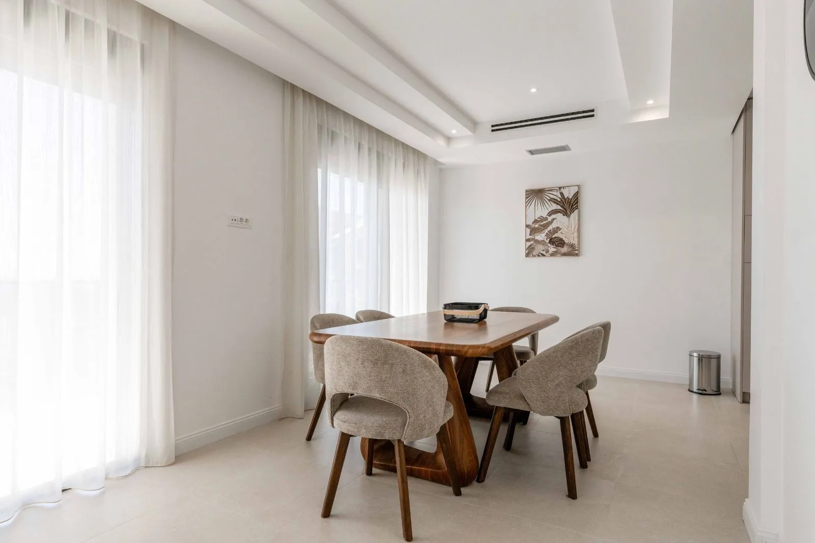 Dining area with a wooden table and upholstered chairs in a bright interior.
