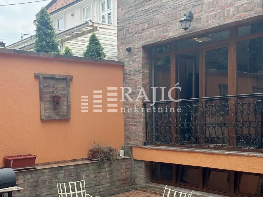 Dvorište kuće sa kamenom fasadom i terasom.