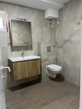 Moderno kupatilo obloženo keramičkim pločicama sa umivaonikom i visećom šoljom. - image 12