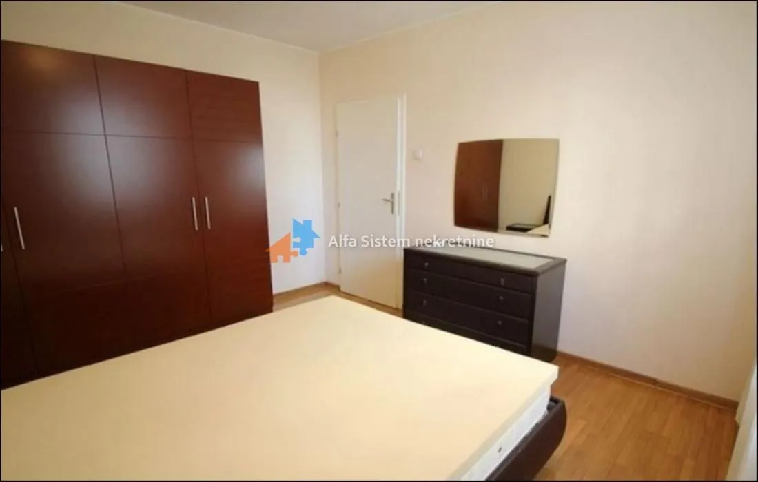 Bedroom with a double bed, large wardrobe, and a dresser with a mirror.
