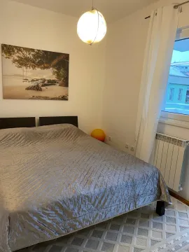 Uređena spavaća soba sa bračnim krevetom, bijelim zavesama i slikom na zidu. - image 4