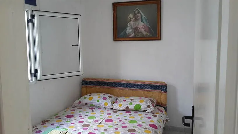 Manja spavaća soba sa bračnim krevetom i prozorom.