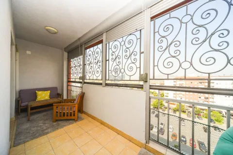 Enclosed balcony with seating furniture and a city view. - image 6