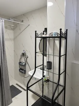 Small bathroom with a shower enclosure, washbasin, and a black metal shelving unit. - image 10