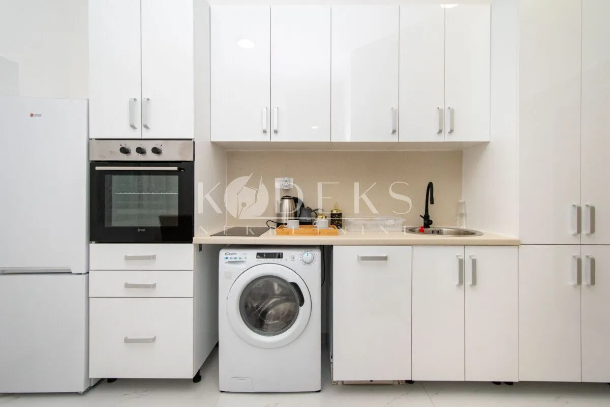 White kitchen with built-in appliances, oven, refrigerator, and washing machine.