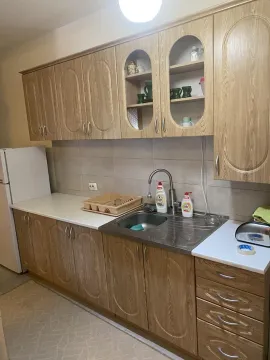 Kuhinja sa drvenim elementima, sudoperom i frižiderom. - image 17