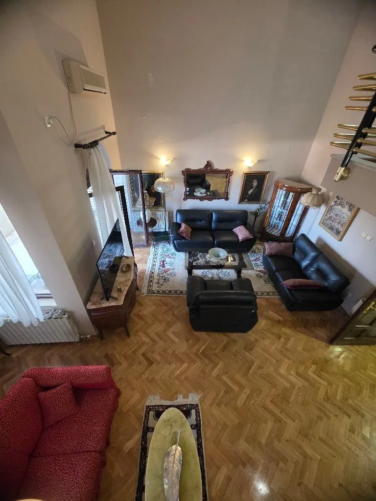 Spacious living room with sofa set and parquet flooring, photographed from the upper level.