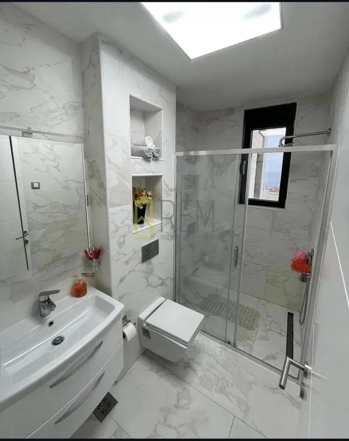 Modernly equipped bathroom with a walk-in shower and marble tiles.