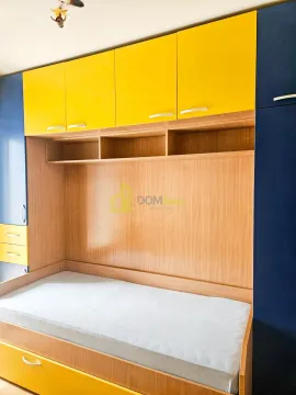 Children's bedroom with a bed and built-in yellow and blue closets. - image 10