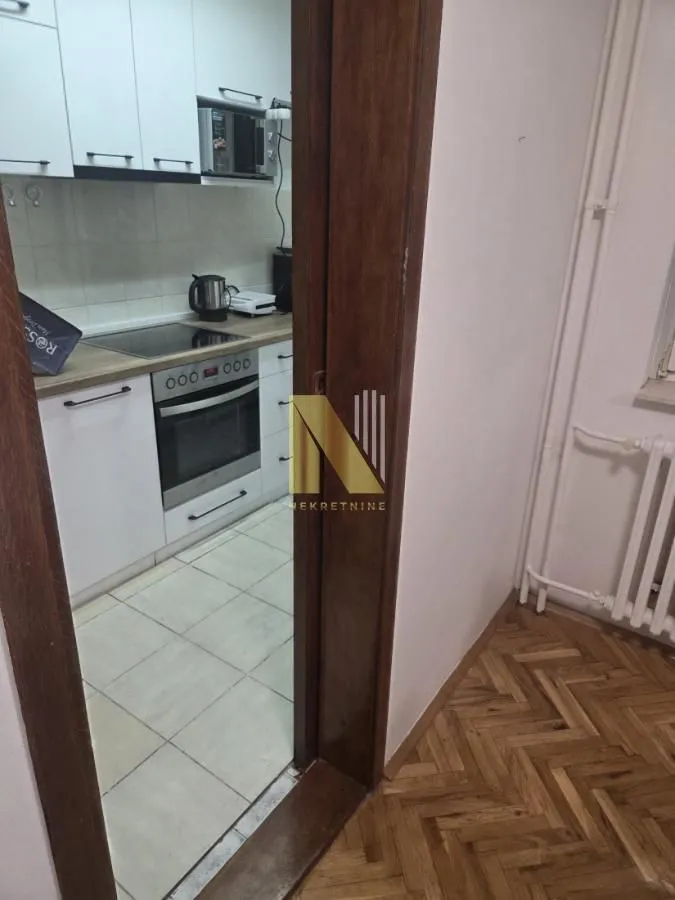 Pogled iz hodnika na manju opremljenu kuhinju.