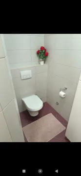 Smaller bathroom with a toilet and light tiles. - image 17