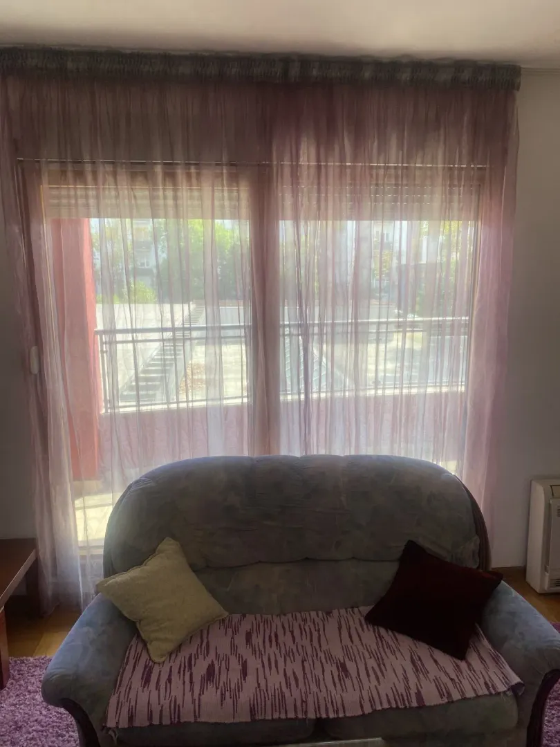 A sofa in front of a window with curtains.