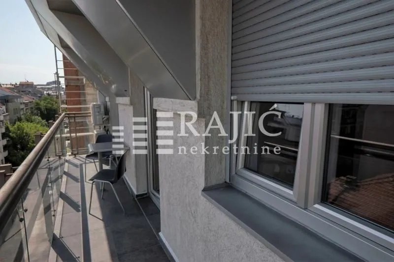 Balcony with a table and chairs and a city view.