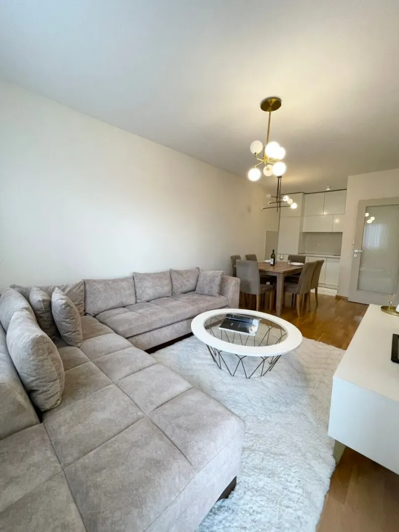 Living room with a sectional sofa, coffee table, and a dining area in the background.
