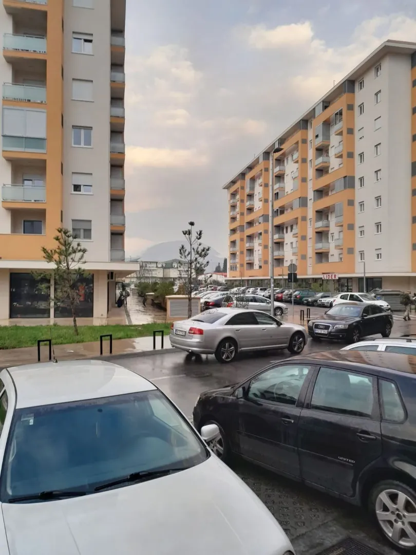 Pogled na eksterijer stambenih zgrada sa parkingom ispred.