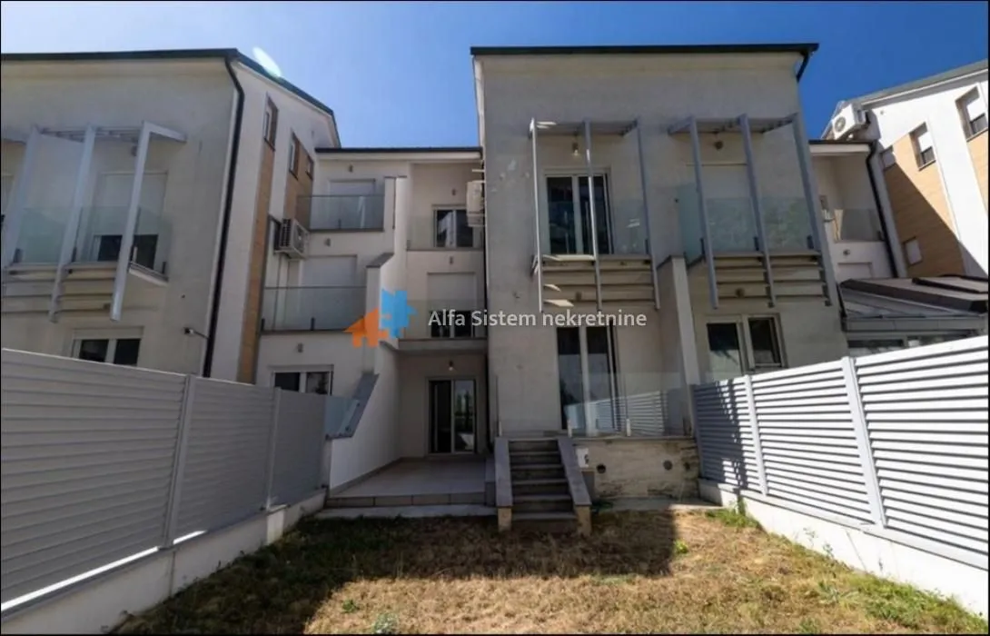 Rear view of the building with a yard and balconies.