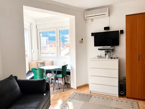 Living room with a sofa, TV, and an enclosed balcony area with a dining table. - image 3