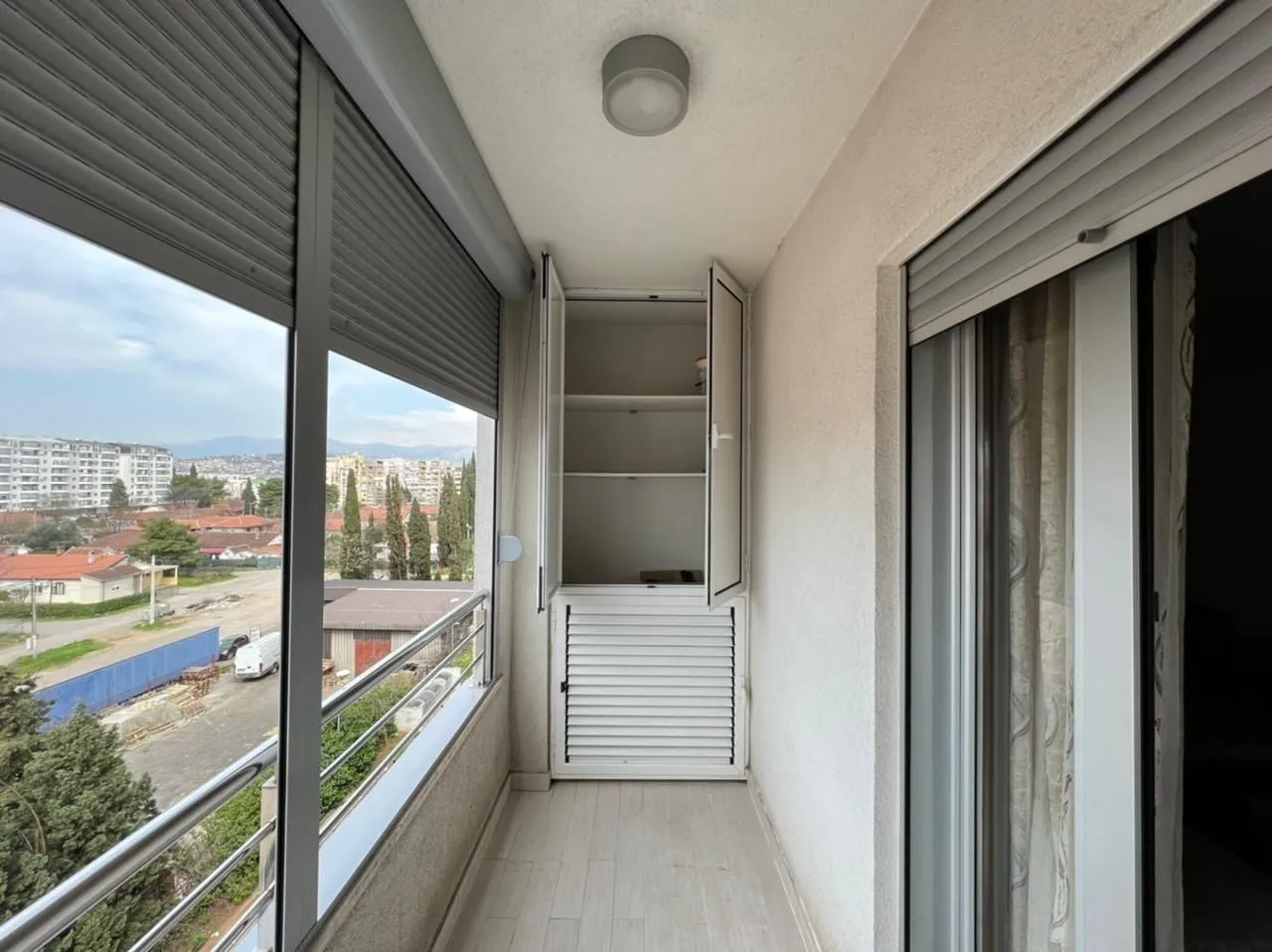 Zatvoreni balkon sa ugradnim ormarom i pogledom.