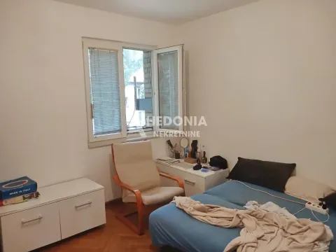 Nameštena spavaća soba sa krevetom, foteljom i prozorom. - image 3